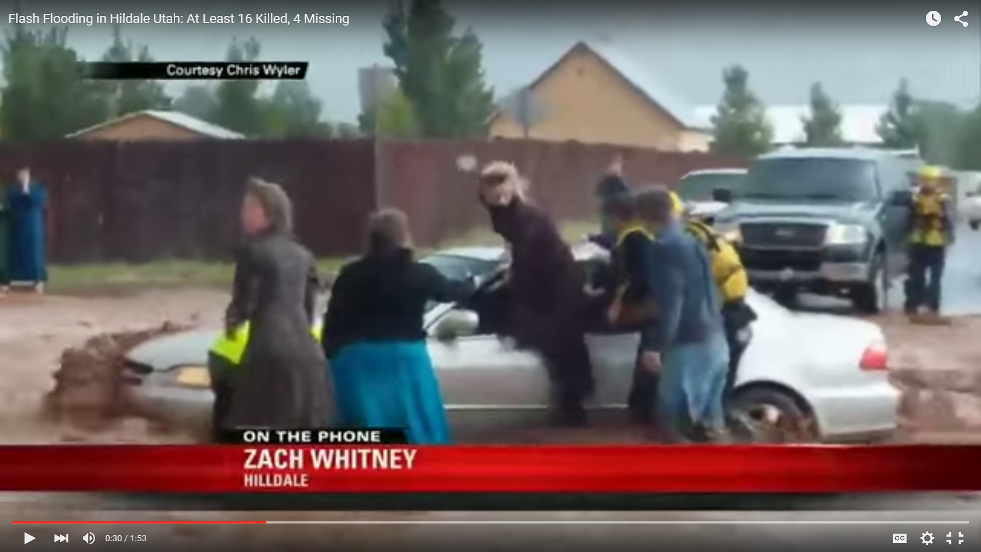 A screen capture of a video showing people being pulled from a trapped car in a flooded roadway in Hildale, Utah.